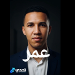 Portrait of a man in a navy suit against a dark background, with white Arabic text across the chest and a logo bottom-left.